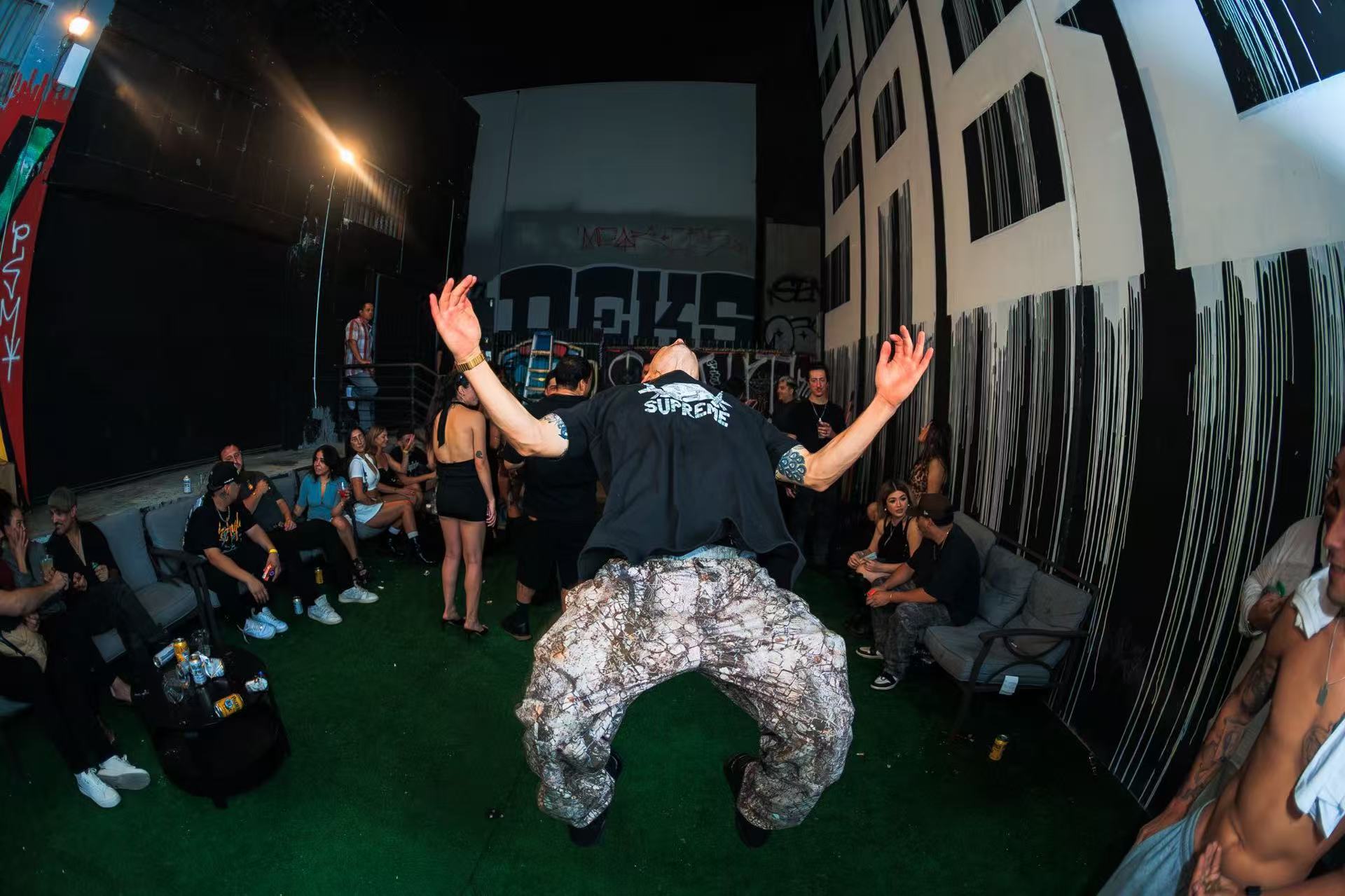 A guest dancing in a courtyard surrounded by seated and standing guests.