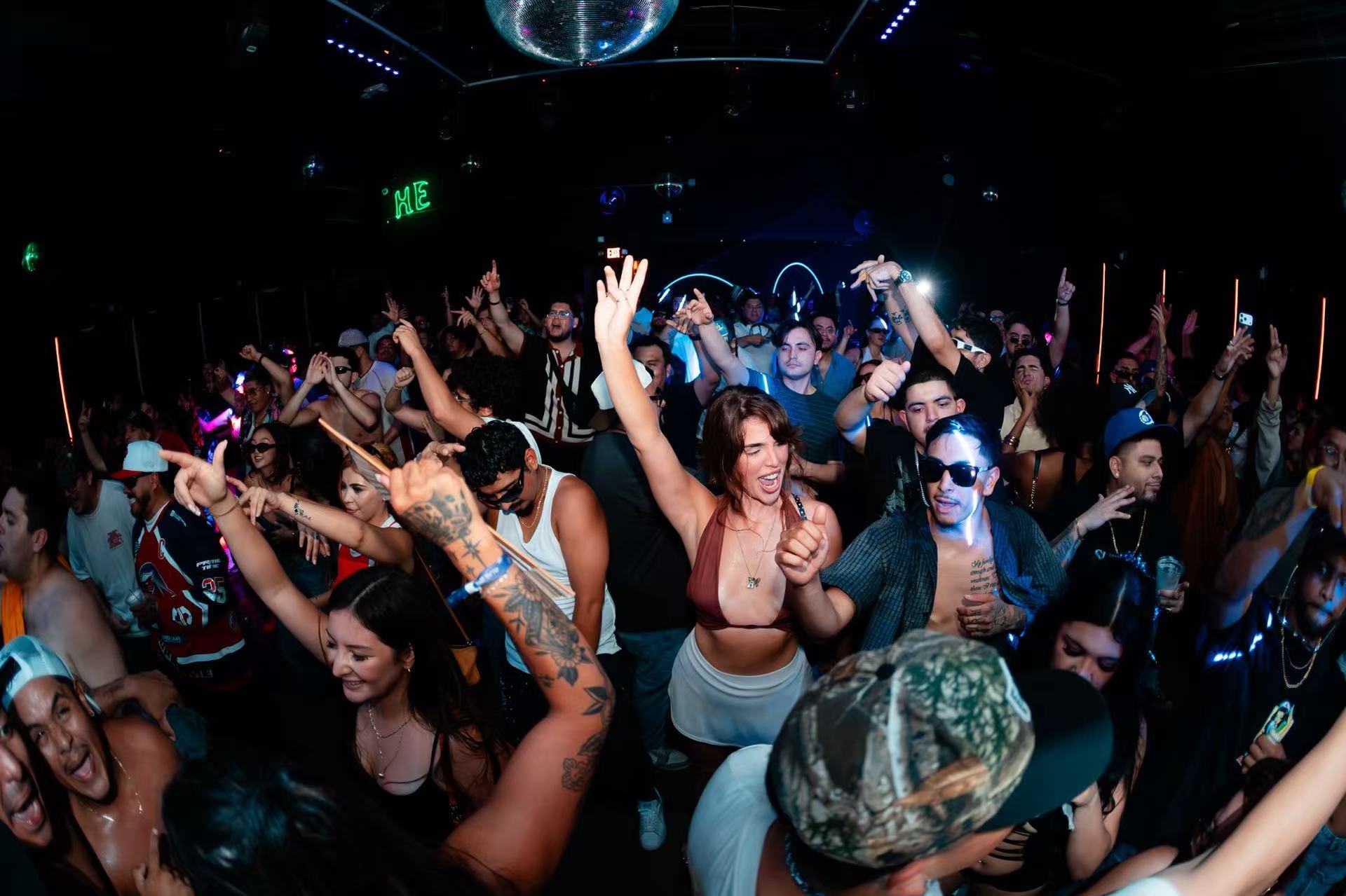 A lively dance-floor crowd raising their hands beneath a mirror ball.