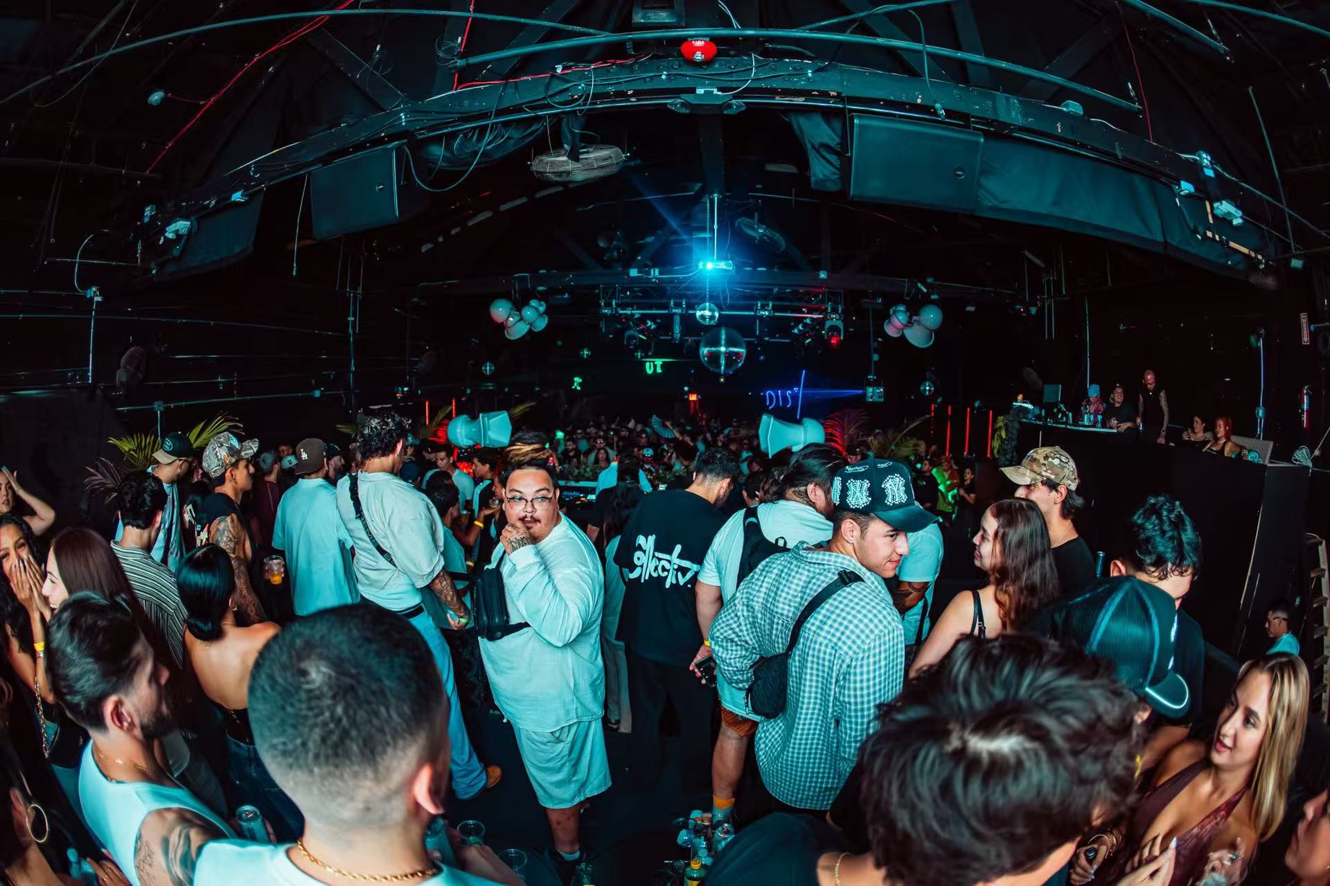 Guests across the dance floor beneath exposed roof beams and blue lighting.